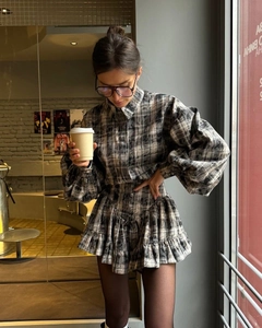 Detail shot of elegant gray plaid dress featuring chic puff sleeves and ruffled hem design
