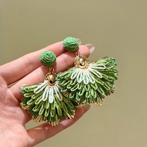 Close-up detail showing the woven texture of green raffia fan-shaped drop earrings