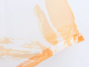 Makroaufnahme von weißem Organza-Stoff mit orangen Pinselstrichen und feinen Saumdetails