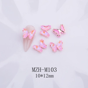 Vista macro de dijes para uñas de mariposa 3D con degradado rosa y base dorada