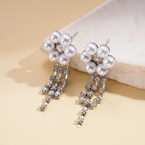 Detailed macro view of sparkling rhinestone tassels and faux pearl flowers on earrings