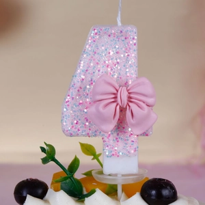 Pink glitter number 4 birthday candle with cute bow decoration on a cream cake