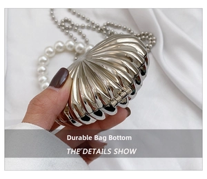 Detail view of shell-shaped silver evening bag with pearl handle and metal hinge design