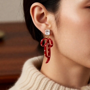 Close-up of vintage red bow earrings with star pattern and zircon on a model wearing a sweater