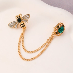 Detail of bee brooch with emerald stones, pearls and dual gold chains on suit lapel