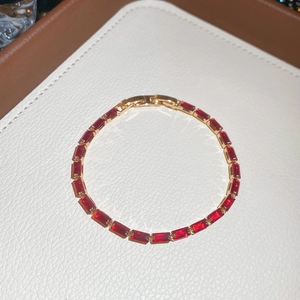 Detailed macro of 18k gold tennis bracelet with baguette cut red rubies on leather