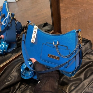 Blue Saffiano leather handbag with golden chain and lettered strap in a lifestyle setting