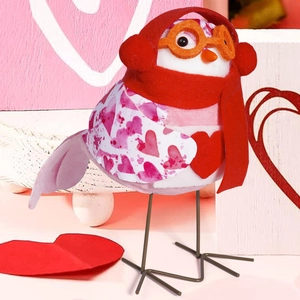 Detailed close-up of a plush Valentine bird doll with heart patterns and red scarf