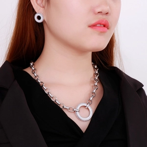 Detail view of silver necklace and earrings set with circular rhinestone pendants on a model