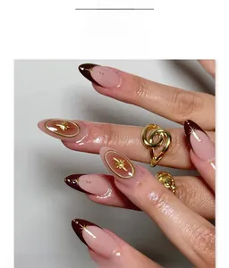 Detail of starburst almond press-on nails with golden star and metal bead accents