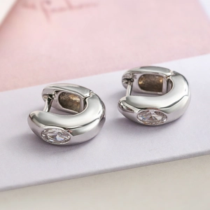 Gros plan sur boucle d'oreille huggie en argent poli avec pierre de zircone claire