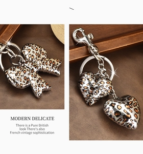 Detail view of leopard print bow and heart charms on a stylish golden metal keychain