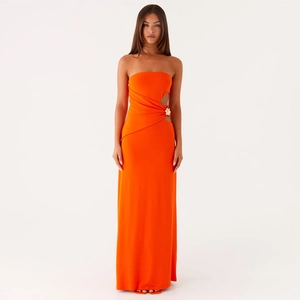 Detalle de vestido largo naranja palabra de honor con recorte y hebilla de flor dorada