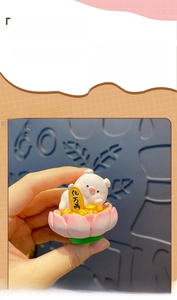 Close-up of a cute resin pig figurine lying on a pink lotus with a gold coin detail