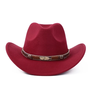 Détail d'un chapeau de cowboy bordeaux avec ruban tressé et ornement plume dorée