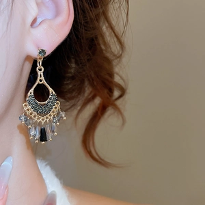 Detailed macro view of vintage hollow-out gold earrings with rhinestones and tassels