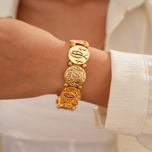 Gros plan du bracelet en métal doré avec breloques gaufrées croix et poisson