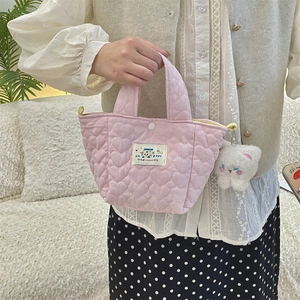 Close-up of pink quilted mini tote bag with Happy patch and plush cat charm