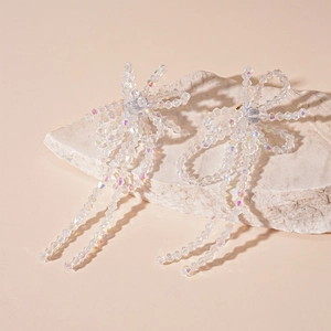 Macro shot of glass crystal bow earrings with long beaded tassels on stone base