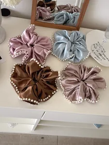 Detail of satin scrunchies with pearl trim in pastel pink, blue, and brown tones