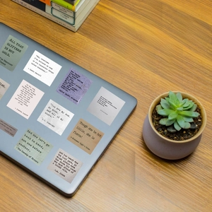 Detail of vintage English quote stickers on a laptop with a rustic wooden desk setting