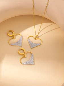 Dettaglio del set di gioielli in titanio a cuore con zirconi scintillanti e finitura oro