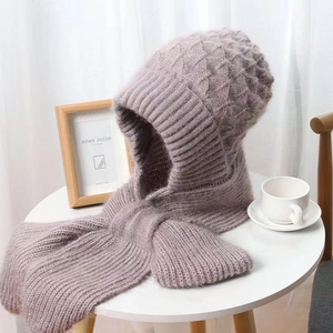 Close-up of chunky knit hooded scarf in dusty rose pink on a minimal white table