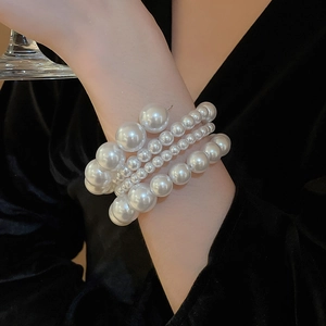 Macro detail of multi-layered spiral pearl bracelet with glossy beads on black fabric