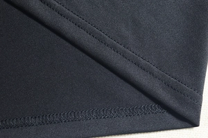 Close-up of double-needle stitching and overlock edge on a black knit dress hem