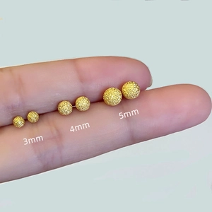 Set de pendientes de bola dorada mate en tamaños 3mm 4mm y 5mm mostrados en el dedo
