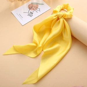 Detailed close-up of a bright yellow satin scrunchie scarf with silk texture and drape