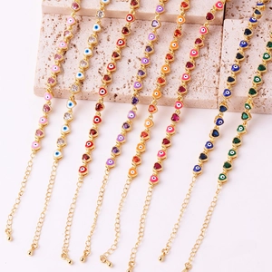 Detail of colorful enamel heart evil eye bracelets on beige stone background in a macro view