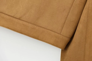 Detailed close-up of brown suede jacket hem with neat double stitching on soft fabric