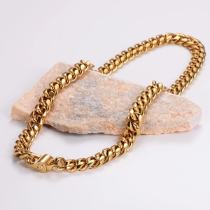 Chunky gold Cuban link chain necklace with cross clasp on pink stone pedestal