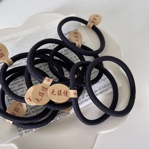 Élastiques à cheveux noirs sans couture empilés sur une assiette blanche avec étiquettes