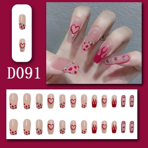 Detail of long coffin press-on nails featuring 3D hearts, flames, and butterfly designs