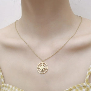 Close-up of golden compass pendant necklace worn on neck with NSEW engravings