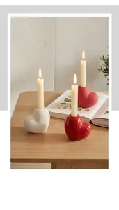 Close-up of heart-shaped ceramic candle holders in glossy red and matte white finish