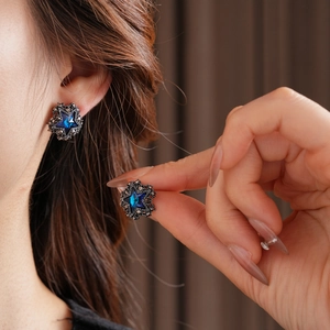 Nahaufnahme von Vintage-Sternohrringen mit blauen Kristallen am Ohr des Models