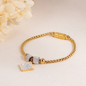 Détail d'un bracelet en chaîne de perles dorées avec pendentif carré en cristal et fermoir magnétique