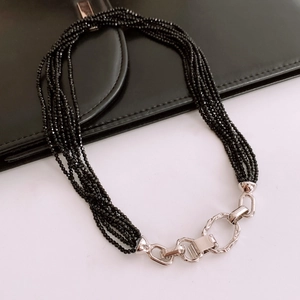 Détail d'un collier de perles noires multicouches avec fermoir argenté rétro sur blanc
