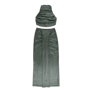 Flat lay of dark green shimmering two-piece set with pleated crop top and high waist skirt