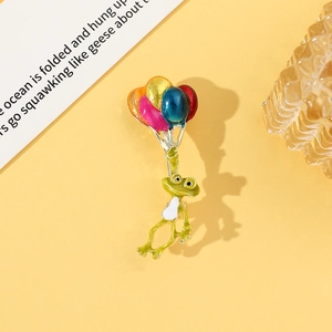 Détail d'une broche grenouille verte tenant cinq ballons colorés en émail brillant