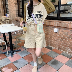 Detail showing a mini checkered crossbody bag paired with high-waisted khaki shorts