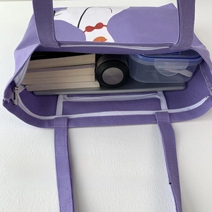 Detail view of purple canvas tote showing large capacity with laptop and books inside