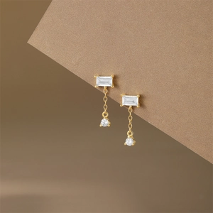 Detail of vintage gold earrings with rectangular crystals and pearls hanging on chains