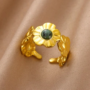 Detail of vintage 18K gold plated flower ring with green stone on textured fabric