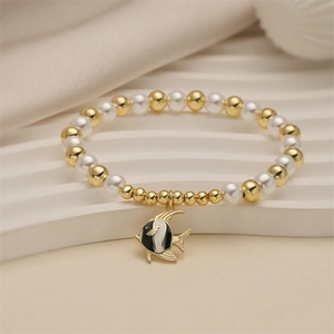 Détail d'un bracelet en perles avec billes dorées et pendentif poisson émaillé noir blanc