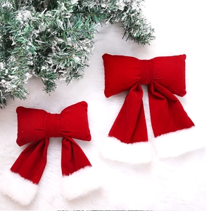 Detail of red velvet Christmas bows with white faux fur trim on a snowy festive branch