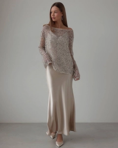Detail von champagnerfarbenem Pailletten-Oberteil und Satin-Midirock am Model